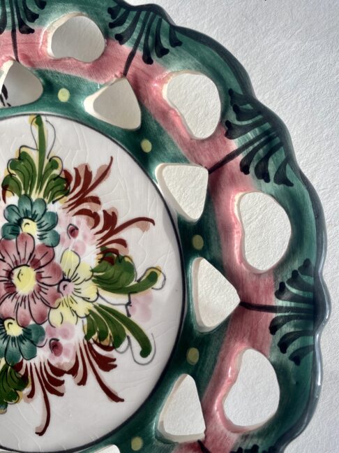 Close-up of a Portuguese wall plate with floral decoration in pinks and greens.