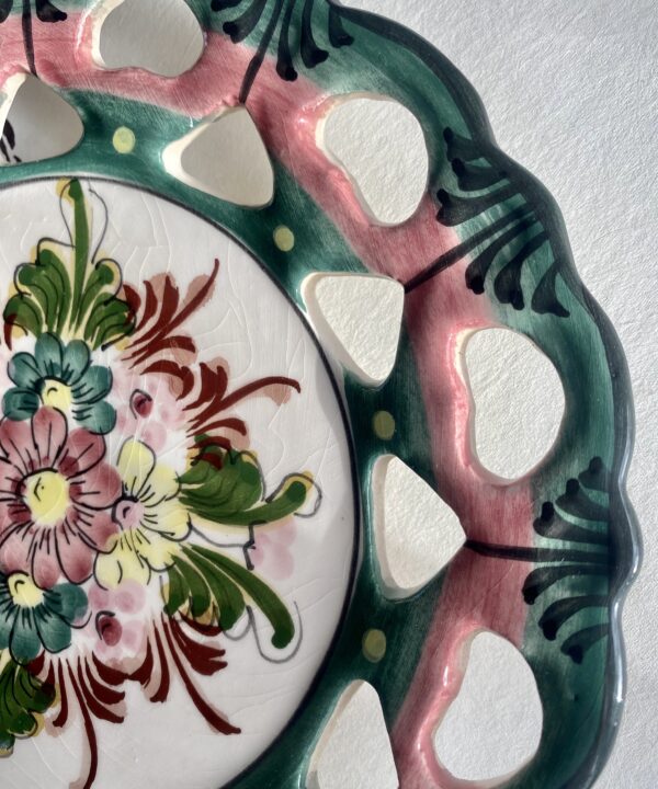 Close-up of a Portuguese wall plate with floral decoration in pinks and greens.