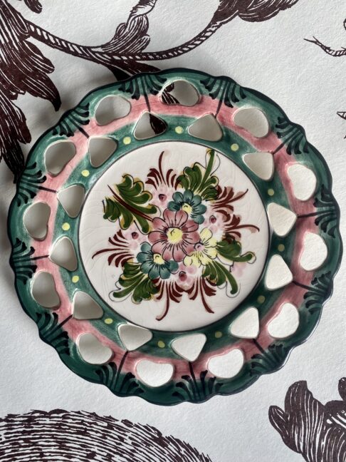 A vintage Portuguese wall plate with pretty floral hand-painted decoration in green and pink.