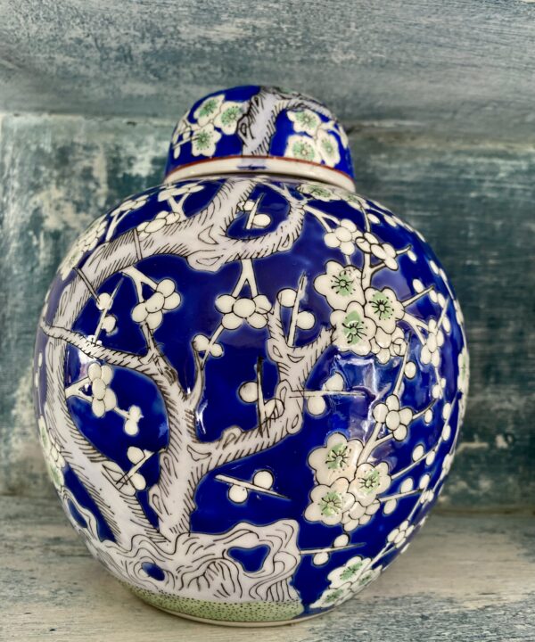 Blue glazed decorative pot with lid depicting a flowering blossom tree in green and white.