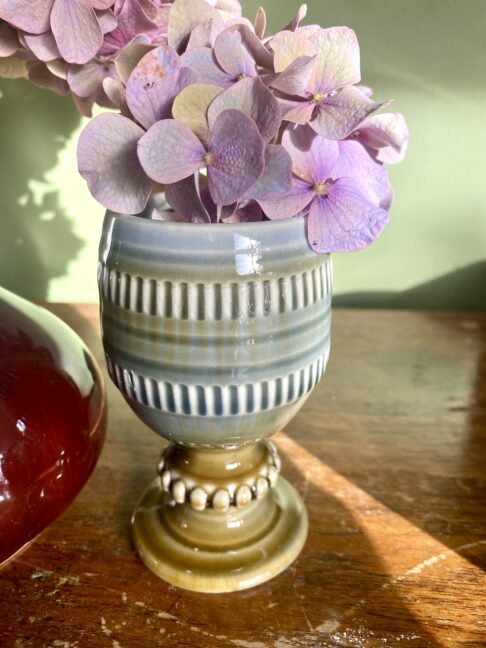 A vintage Irish pottery bud vase or goblet by Wade, filled with dusky pink hydrangea blooms.