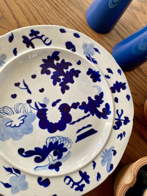 An antique blue and white Staffordshire pearlware plate dating from the mid-19th century shown here on a wooden table.