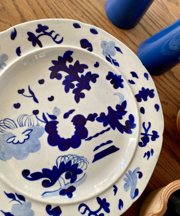 An antique blue and white Staffordshire pearlware plate dating from the mid-19th century shown here on a wooden table.