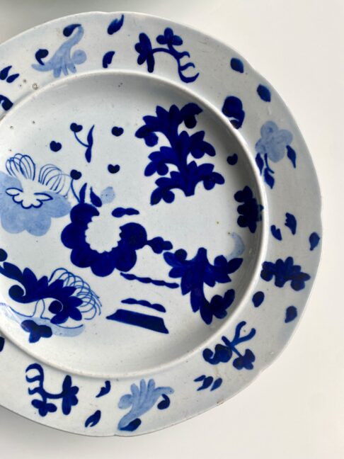 An antique blue and white plate for wall decoration, with Chinese-inspired, hand-painted detailing.