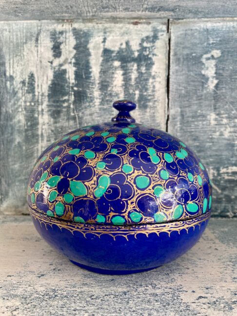 Indian papier mâché box with domed lid in vibrant Royal blue with gilt and green accents. Styled on antiqued blue shelving.