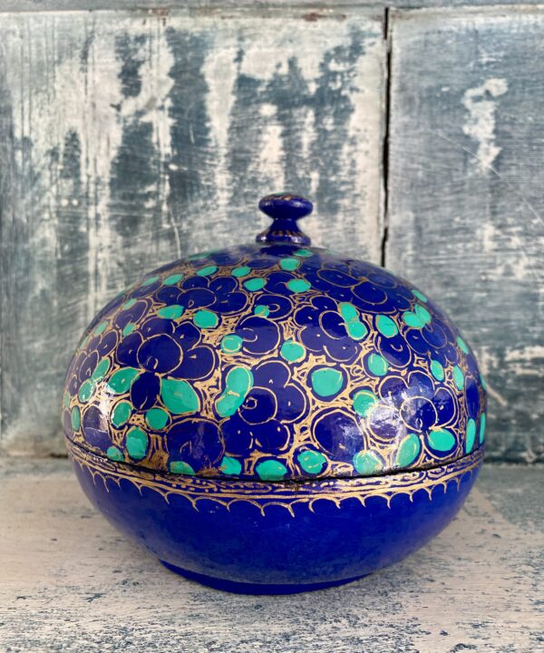 Indian papier mâché box with domed lid in vibrant Royal blue with gilt and green accents. Styled on antiqued blue shelving.