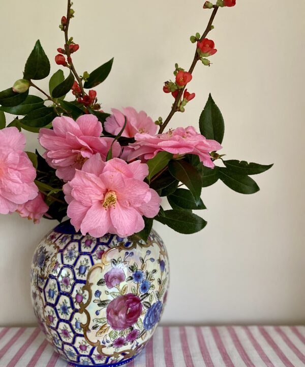 A vintage Chinese vase filled with pink camelias and blossom twigs.