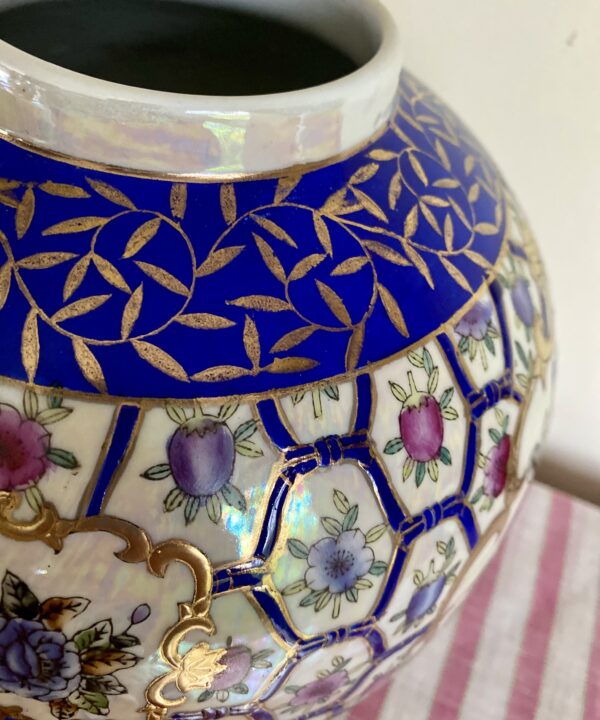 The neck and rim of a vintage Chinese globe vase with florals in pink and blue and gilt detailing.