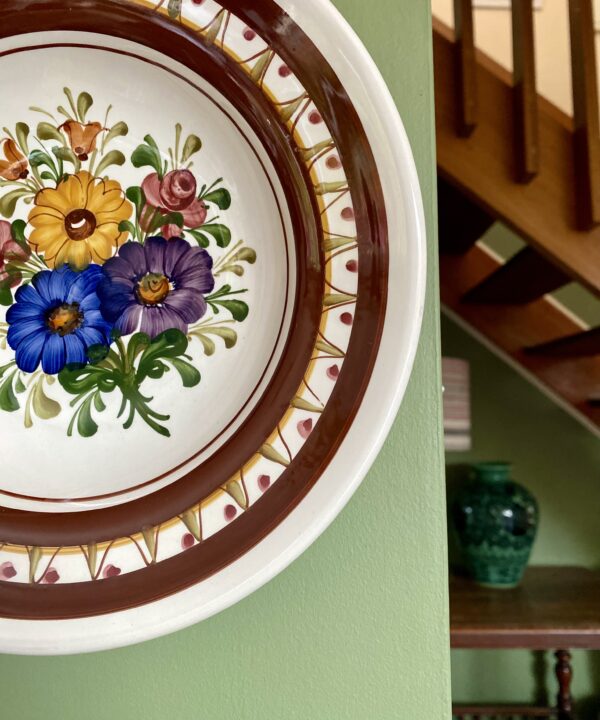 A hand-painted floral design on a decorative, Austrian wall plate.