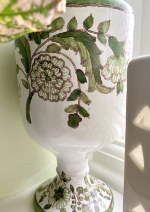 Green, hand-painted floral detailing on a vintage Portuguese vase.