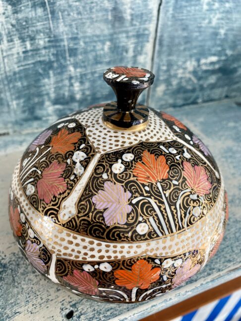 Detail of intricate, hand-painted decoration on a papier mâché Indian trinket pot with domed lid.