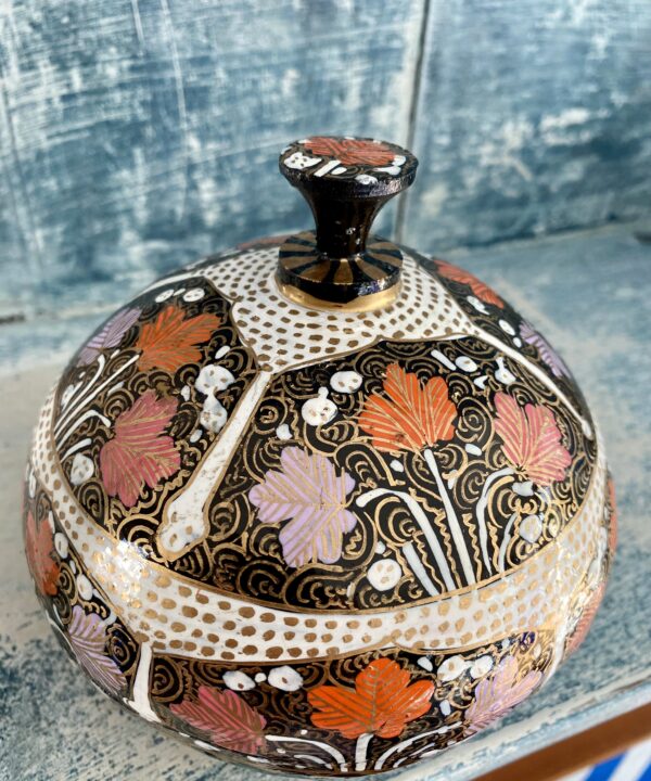 Detail of intricate, hand-painted decoration on a papier mâché Indian trinket pot with domed lid.