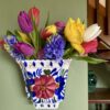 A hand-painted vintage wall vase with floral decoration, itself filled with Spring blooms.