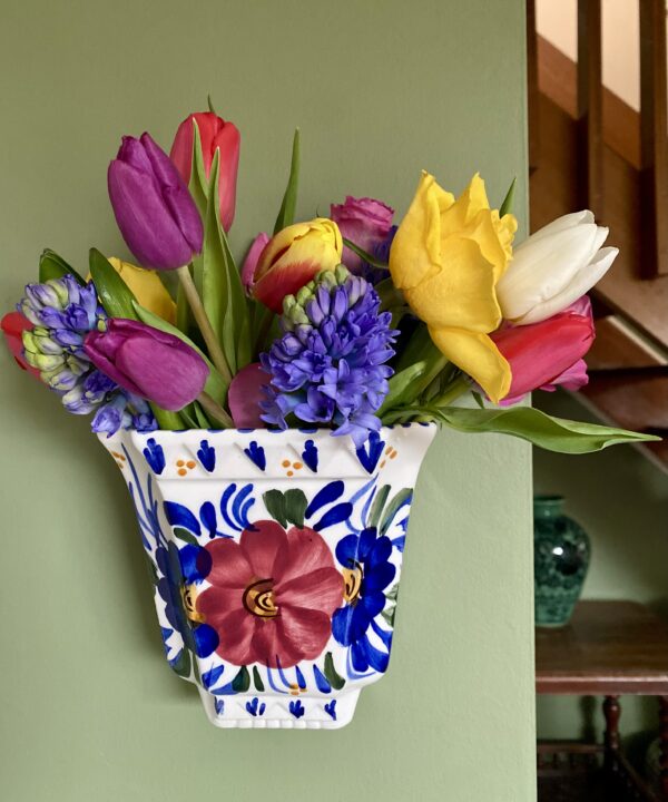 A hand-painted vintage wall vase with floral decoration, itself filled with Spring blooms.