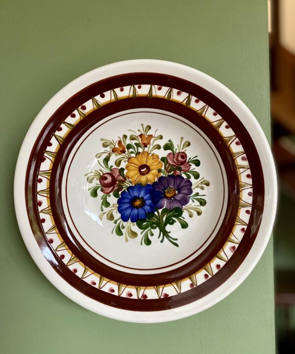 A colourful wall plate with flower decoration.