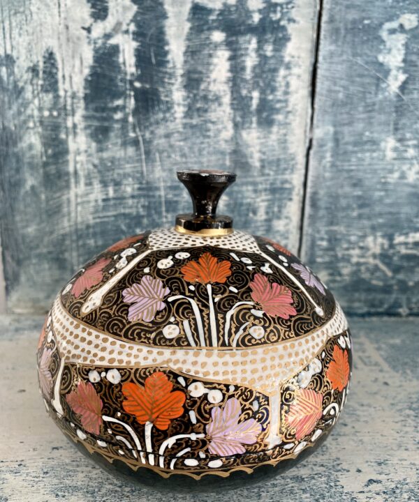 A vintage Indian papier mâché trinket pot with domed lid in pink, orange and lilac with gold detailing.