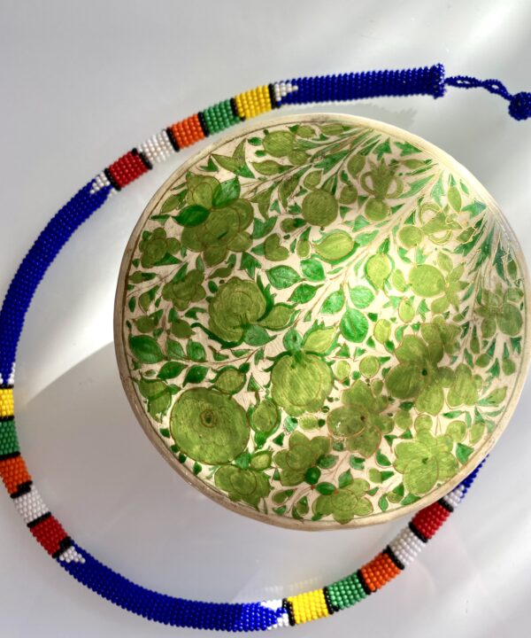 Papier mâché trinket pot in green shown on a glass surface with an African beaded necklace.