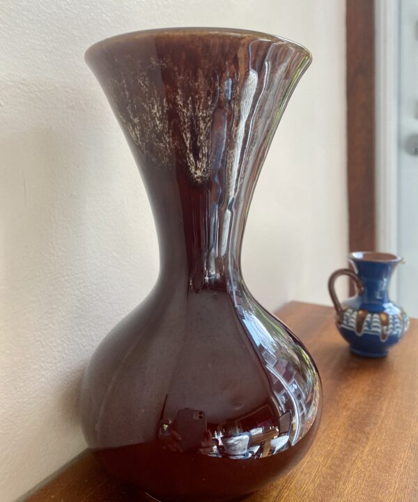 The sinuous curves of a retro 1970s ceramic vase in glossy brown.