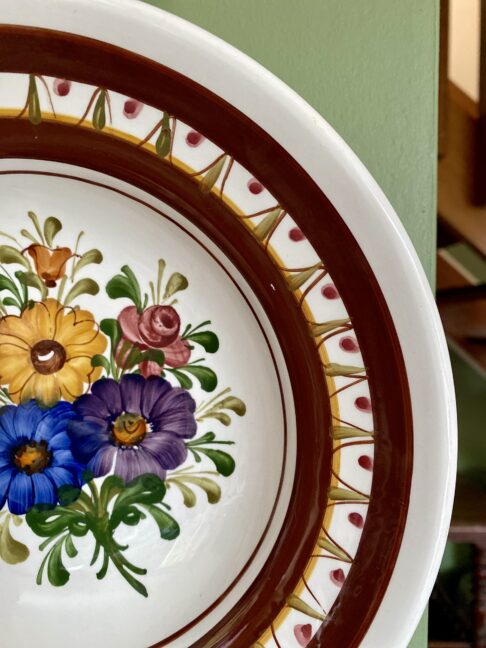 Blue, yellow, pink and purple flowers design on a hand-painted wall plate from Austria.