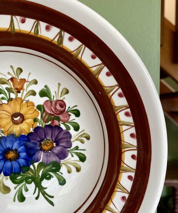 Blue, yellow, pink and purple flowers design on a hand-painted wall plate from Austria.