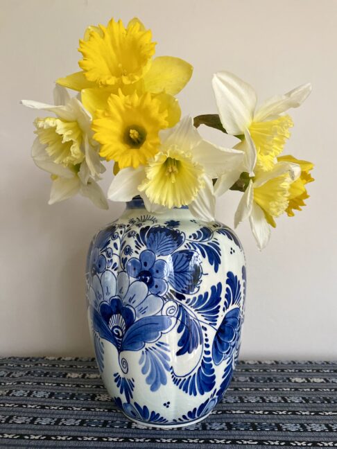 A vintage Delft vase in blue and white floral design. Shown here filled with Spring daffodils.