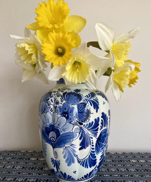 A vintage Delft vase in blue and white floral design. Shown here filled with Spring daffodils.