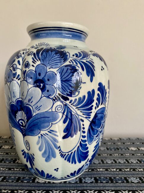 A Delft vase intricately hand-painted with flowers in blue.