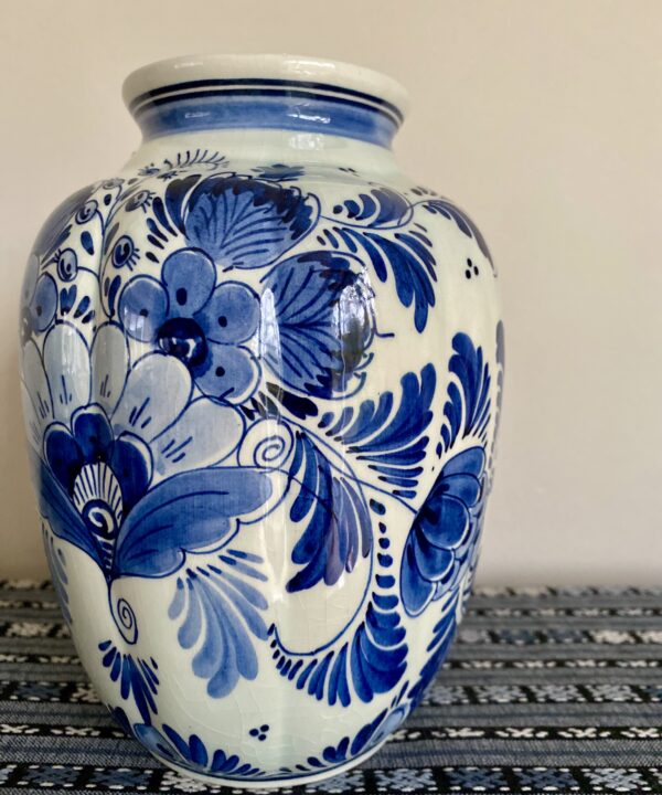 A Delft vase intricately hand-painted with flowers in blue.