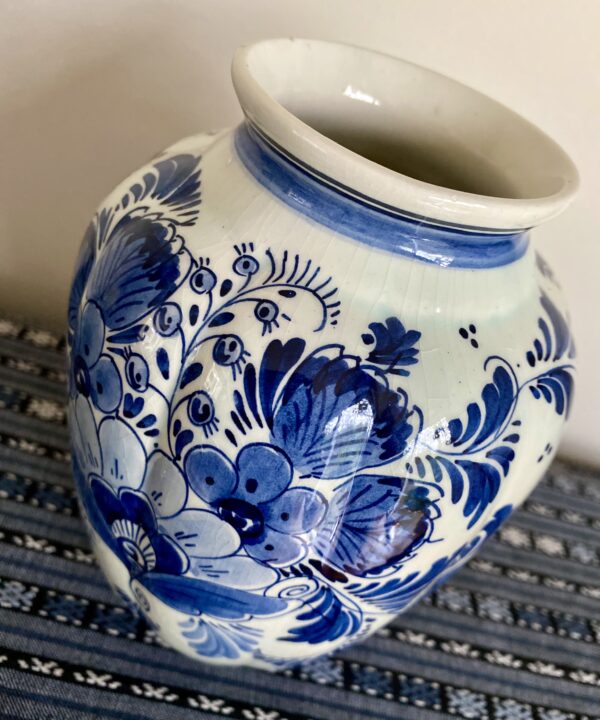 An elegant Delft vase with flowers hand-painted in blue.