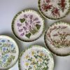A vintage hand-painted floral wall plate set hailing from Paphos, Cyprus.