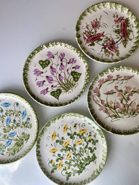 A vintage hand-painted floral wall plate set hailing from Paphos, Cyprus.
