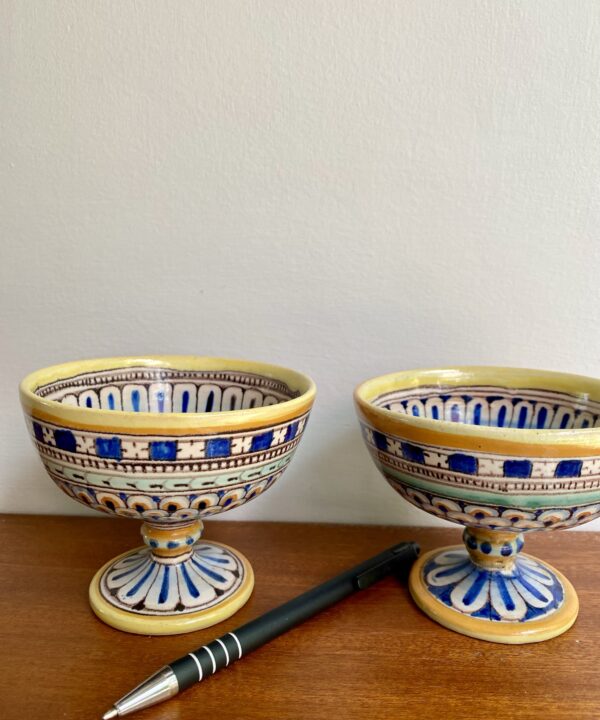 Two diminutive, hand-painted ceramic dishes in blue and yellow.