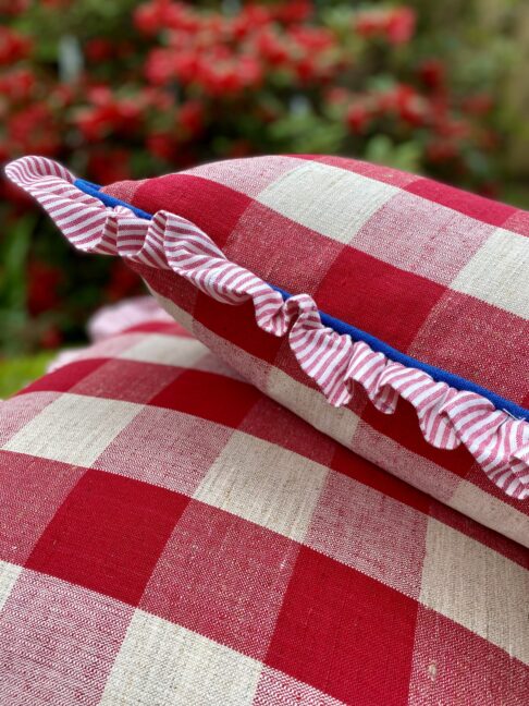 Large red check cushions with a striped ruffle and blue piping.