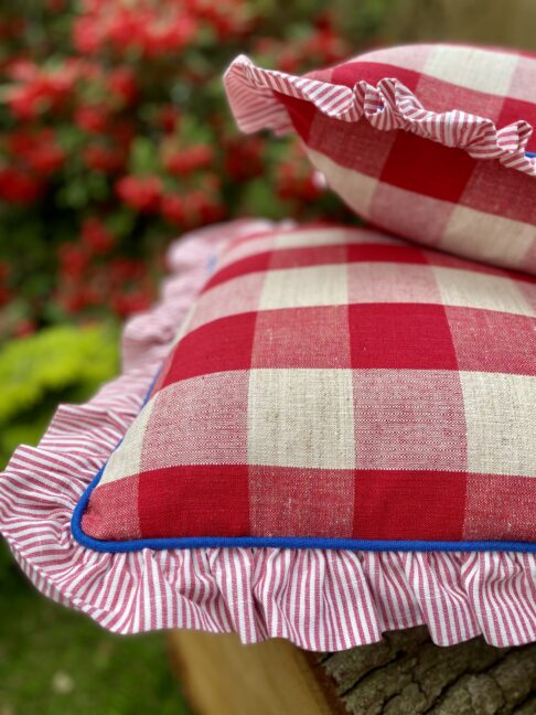 Frilled cushions in red check with blue piping.