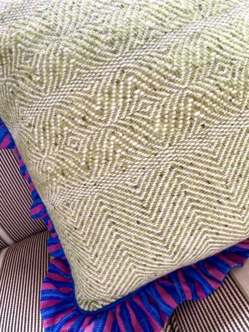 Handwoven Irish tweed cushion cover in lime green with a frilled, linen trim in contrasting blue and pink.