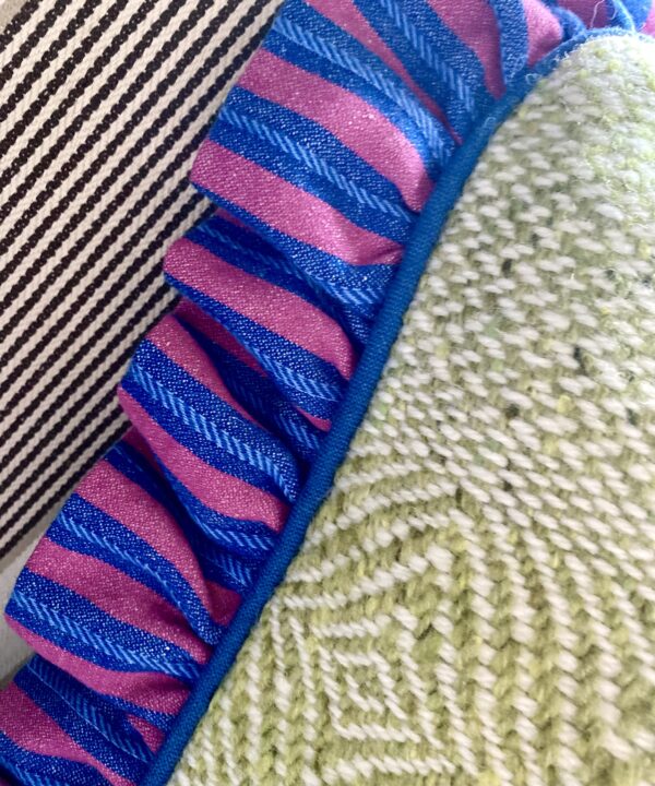 Irish linen frill on a green tweed cushion in pink and blue stripes.
