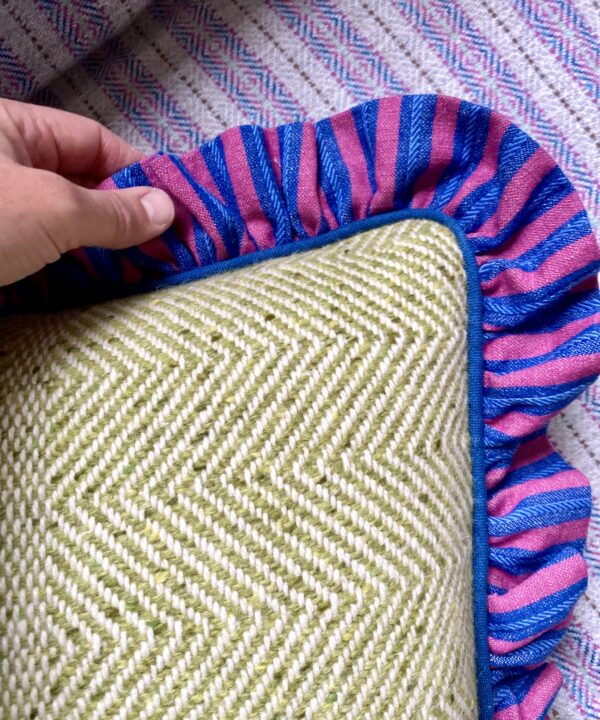 A handmade tweed cushion in lime green with a striped linen frill.
