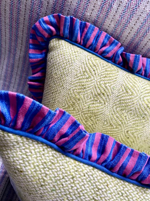 Deep pink and cobalt blue frilled linen edge on a tweed cushion in pale green.