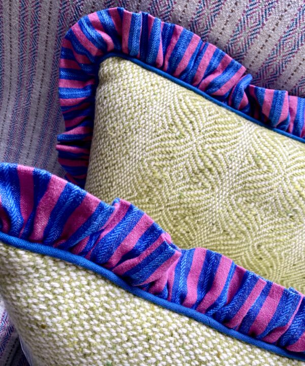Deep pink and cobalt blue frilled linen edge on a tweed cushion in pale green.