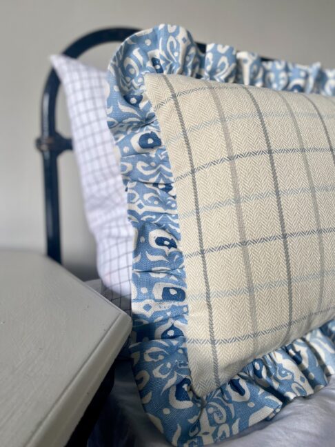 A pretty pale blue frilled linen cushion with a check reverse.