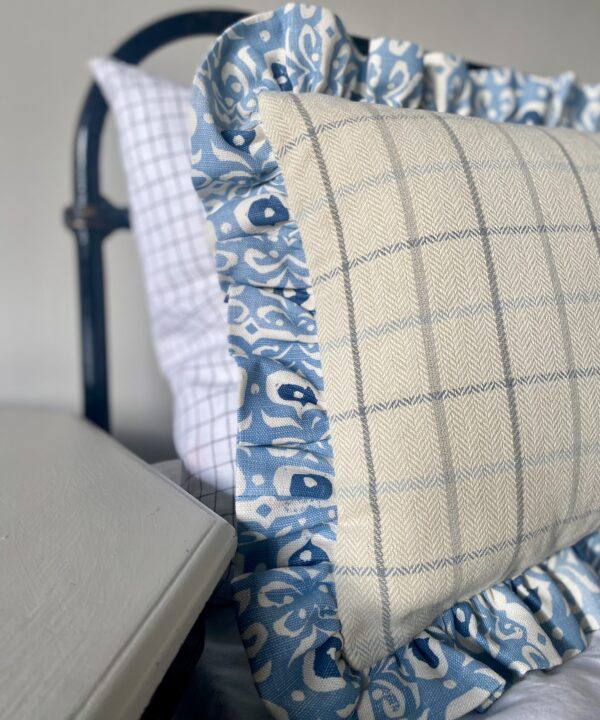 A pretty pale blue frilled linen cushion with a check reverse.