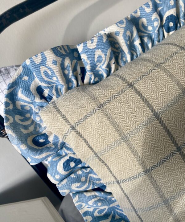 Detail of a plaid cushion in cream and blue with a hand-print linen frill.