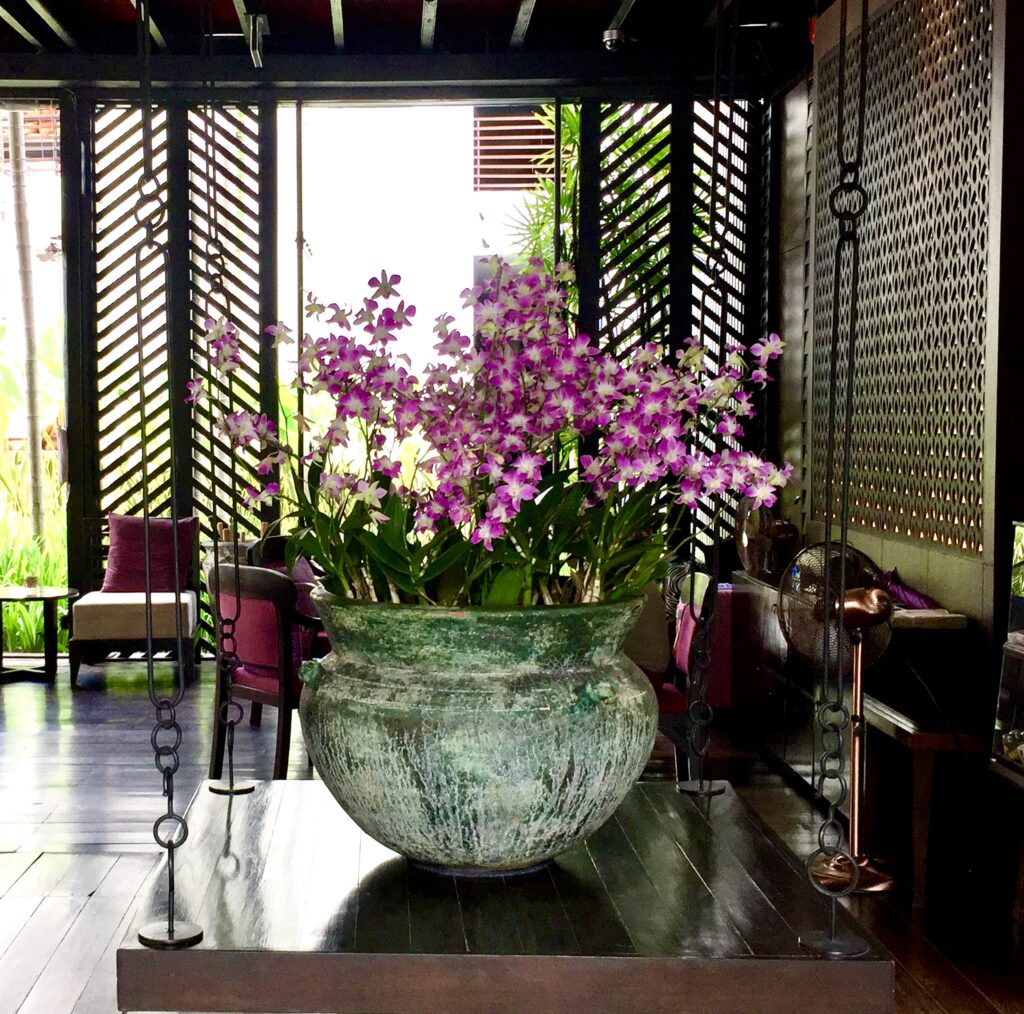 A large verdigris copper bowl filled with pink orchids at a hotel in Thailand.