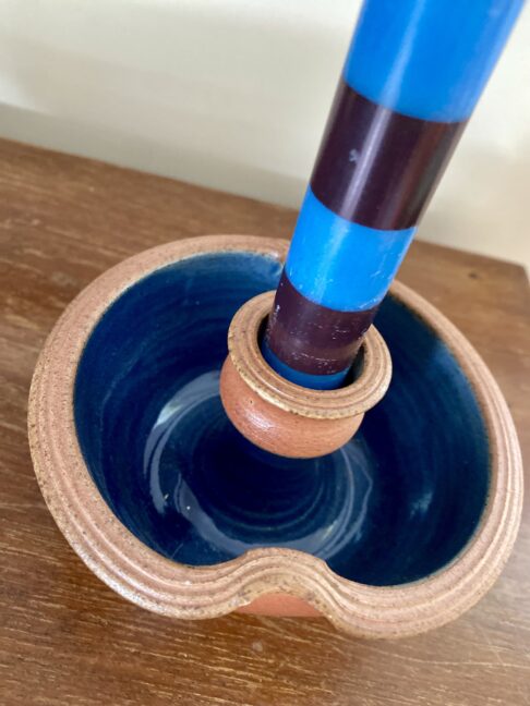 A blue and terracotta-coloured rustic candle holder made by a Scottish artisan potter.